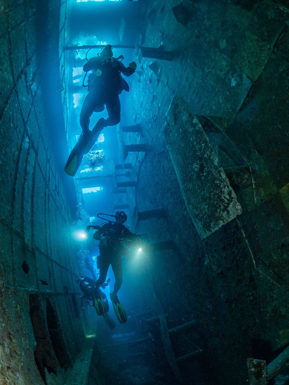 several divers against the light in a wreck 